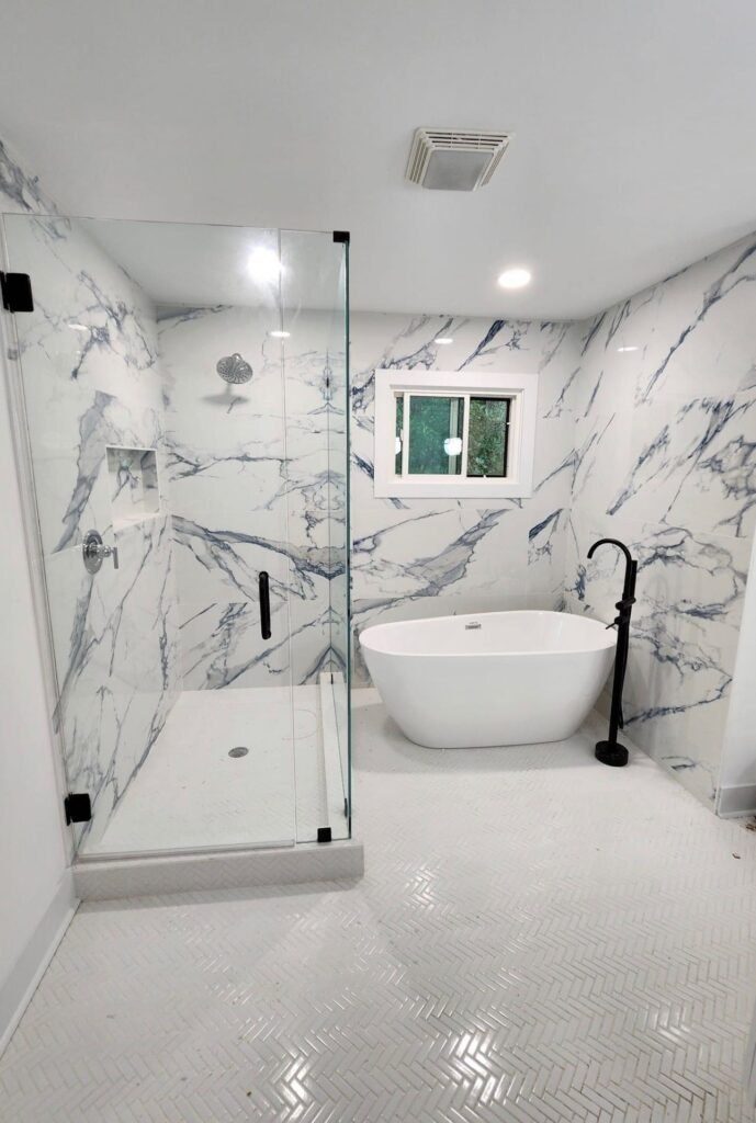 Bathroom with glass shower, marble-look tile and freestanding tub