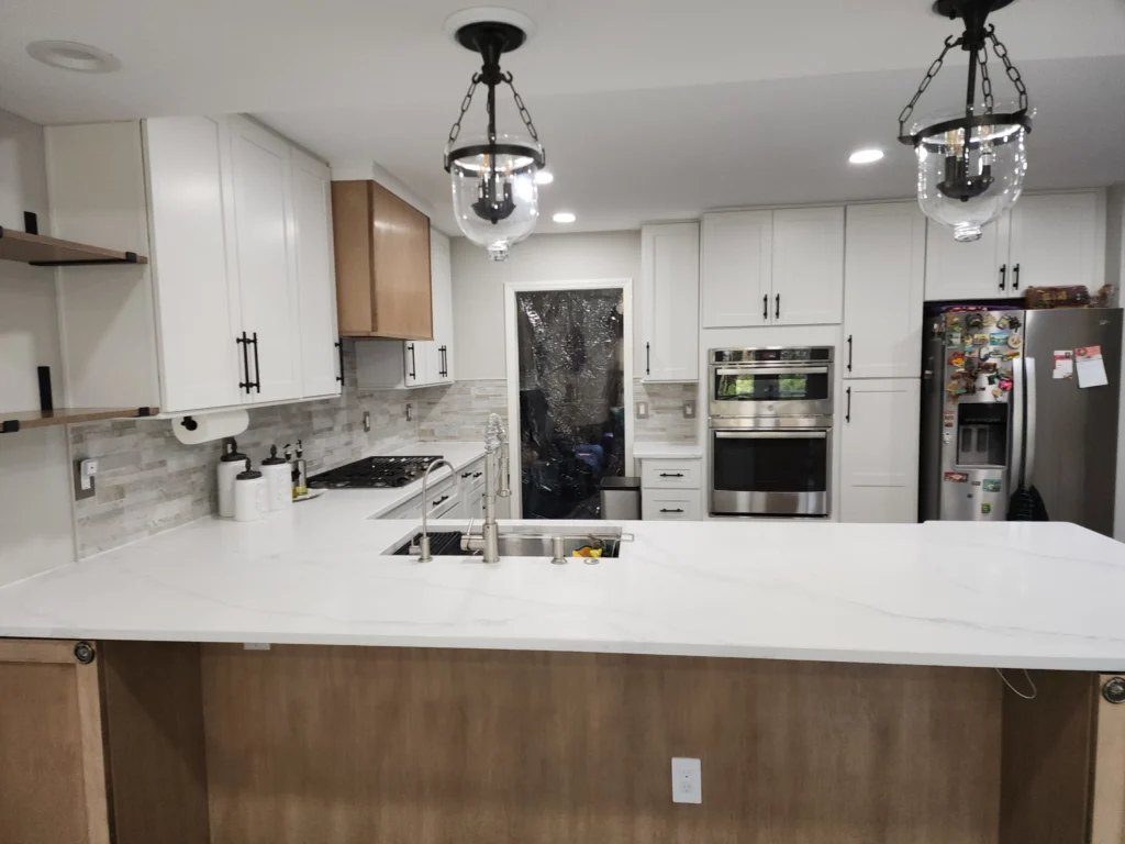 Full kitchen remodel with island, white cabinetry and pendant lights